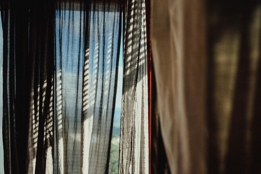 Soft sunlight filtering through sheer curtains, casting shadows indoors.